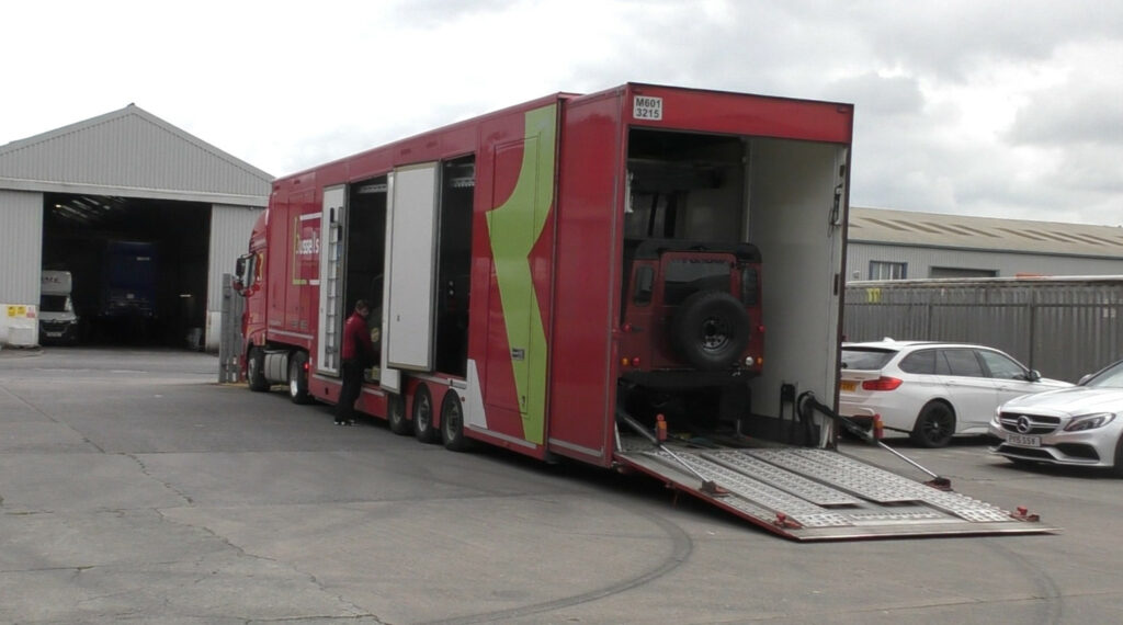 Specialist covered vehicle transporter carrying two luxury custom Land Rovers, on arrival at the Autoshippers warehouse